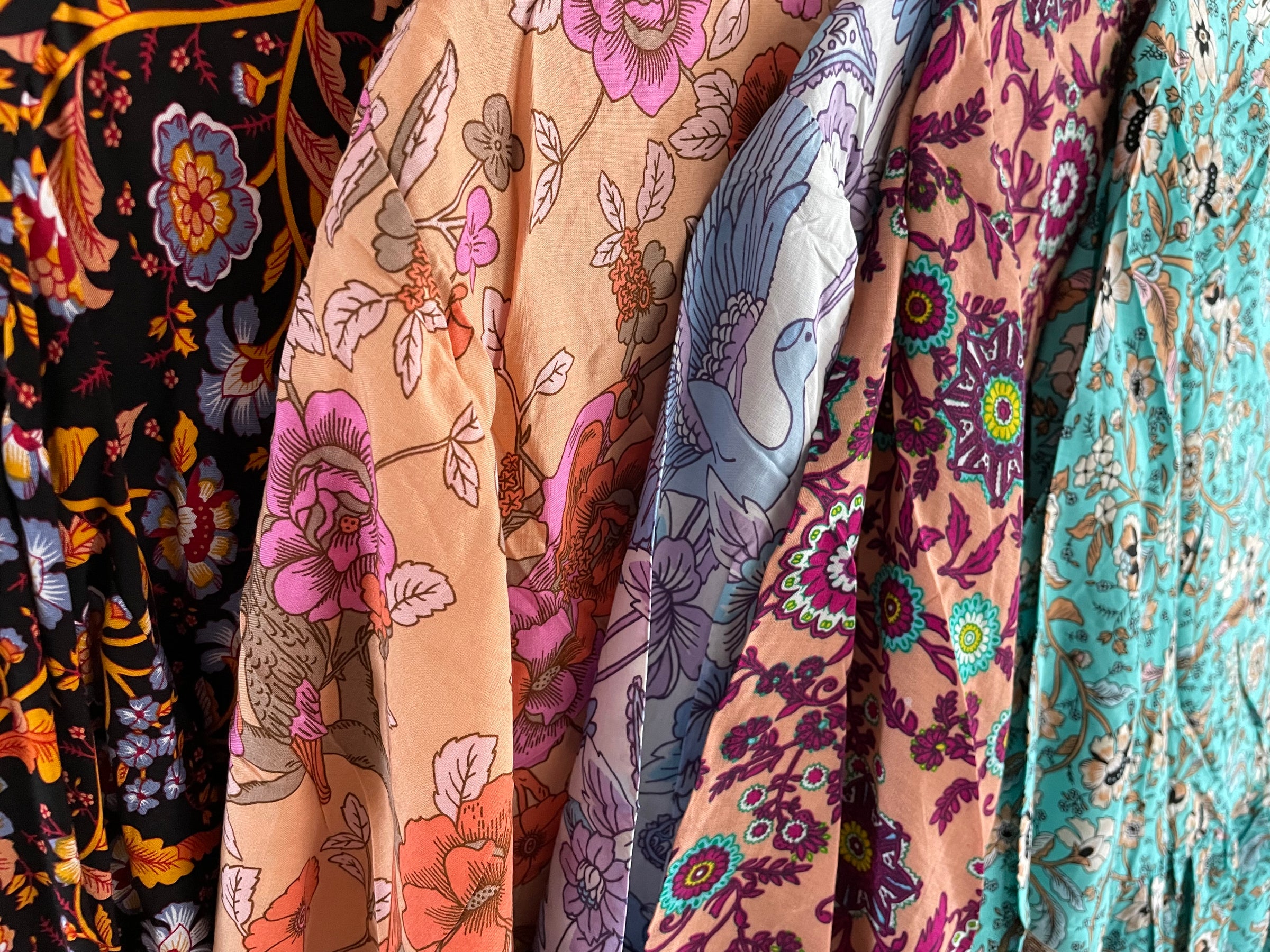 A close view of clothing on hangers, showing a variety of colourful-patterned fabrics